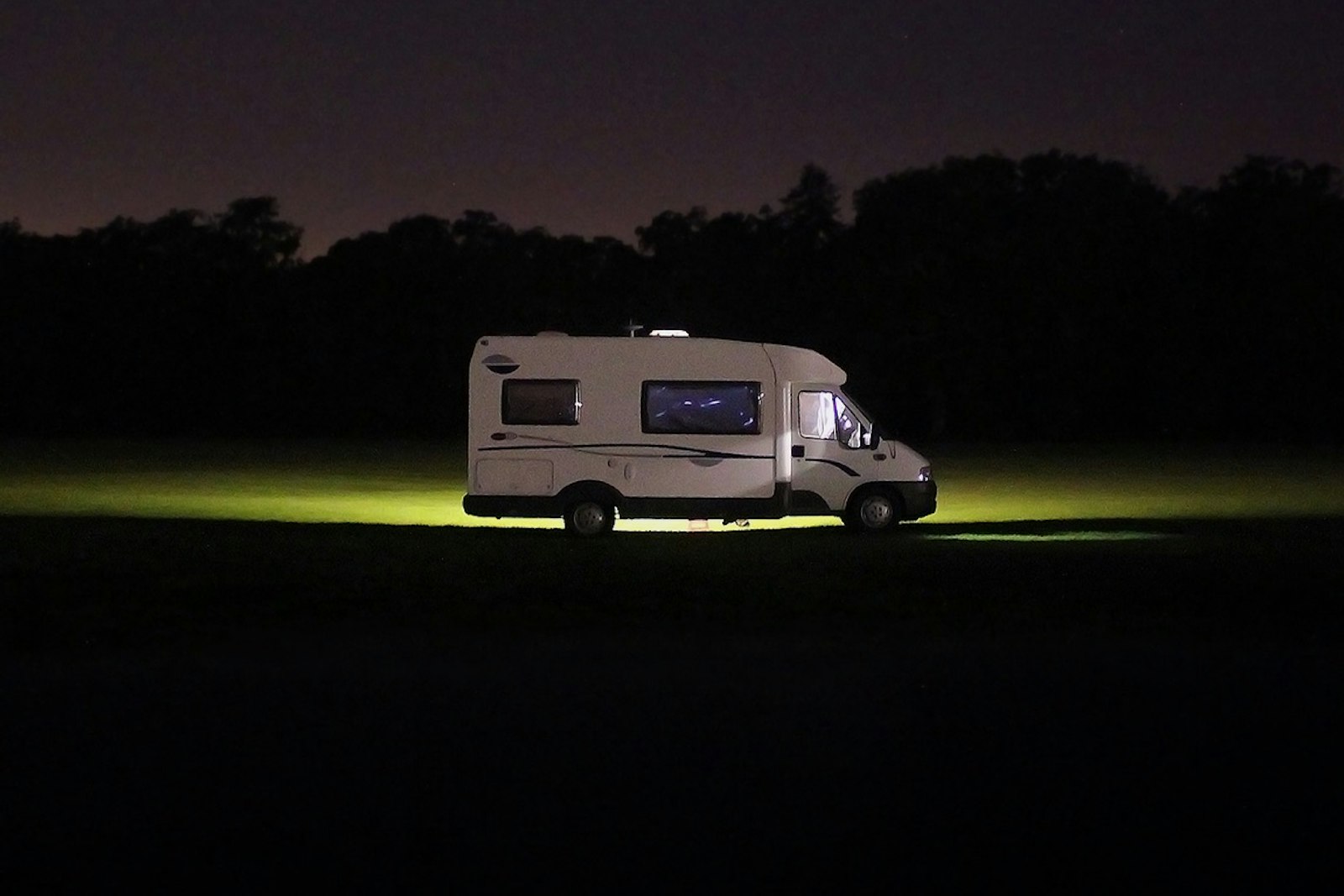 A motorhome parked on a dark field at night
